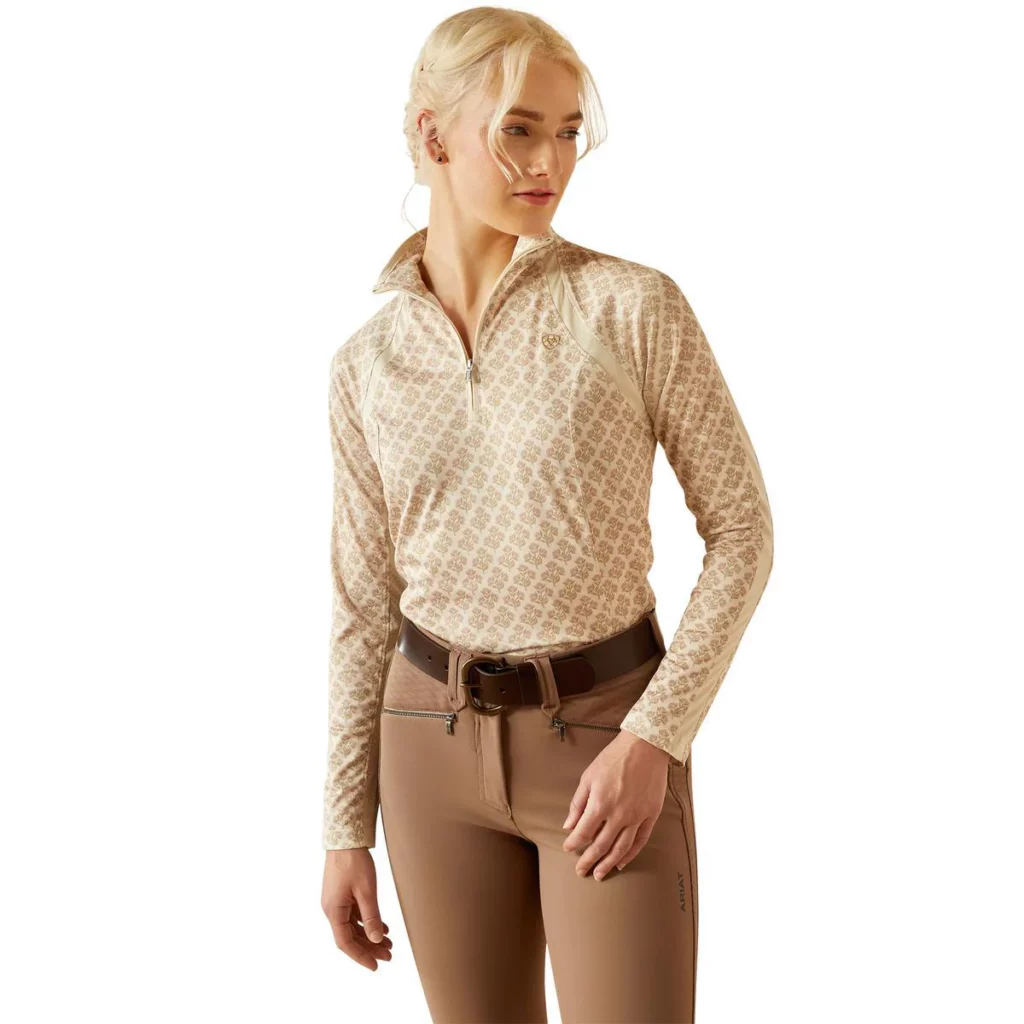 Woman wearing light brown patterned 1/4 zip baselayer with brown breeches